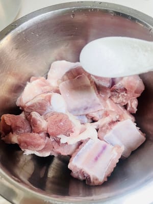 Marinasi iga
Dalam mangkuk besar, letakkan iga yang sudah ditiriskan. Tambahkan 3 iris jahe, 20 ml arak masak, 2 g lada putih, dan 3 g garam. Tambahkan 25 g jus markisa dan 20 g jus nanas. Aduk rata dengan tangan, tutup dengan plastik wrap, dan marinasi di lemari es selama 4 jam (semakin lama marinasi, semakin kaya rasanya).