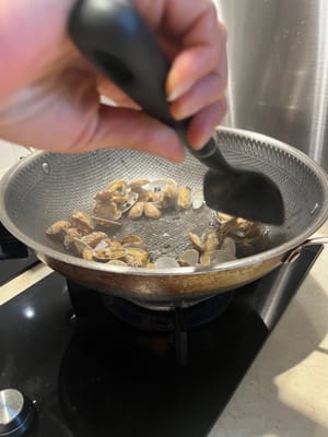 Dann die blanchierten Muscheln hinzufügen und 30 Sekunden lang anbraten.