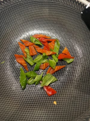 Eine Pfanne erhitzen, etwas Öl hineingeben, die grünen und roten Paprikaschoten in die Pfanne geben, etwas Salz hinzufügen und braten, bis sie zu 70 % gar sind.