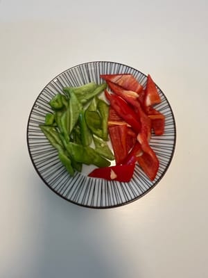 Grüne und rote Paprika in kleine Stücke schneiden