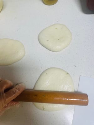 Spruzzare un po' d'olio sul piano di lavoro e sui guanti, estrarre l'impasto lievitato e dividerlo in 5 palline. Con un mattarello stendere la pasta sottilmente, aggiungere il ripieno e chiudere la parte superiore come un panino, con la parte superiore rivolta verso il basso. Quindi, rendere la pasta un po' più sottile e lasciarla riposare per 20-30 minuti per farla lievitare di nuovo.