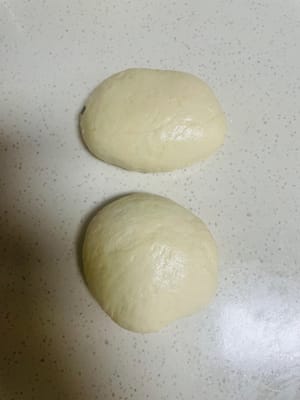 Vaporisez un peu d’huile sur le plan de travail et les gants, sortez la pâte fermentée et divisez-la en 5 boules. À l’aide d’un rouleau à pâtisserie, étalez-la finement, ajoutez la garniture et fermez le dessus comme un petit pain, dessus vers le bas. Ensuite, affinez légèrement la pâte et laissez-la reposer 20 à 30 minutes pour la laisser fermenter à nouveau.