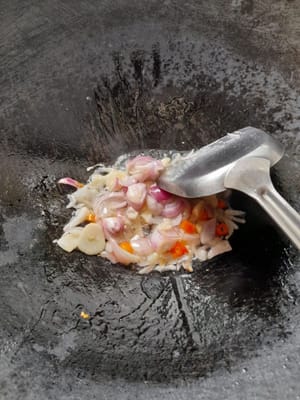 Bereiten Sie eine Bratpfanne vor, geben Sie 2 Esslöffel Öl hinein, schalten Sie die Hitze niedrig ein, braten Sie Knoblauch, Schalotten und Chilis an, bis sie duften und welk sind, geben Sie Rührei, Würstchen und Fischbällchen hinzu.