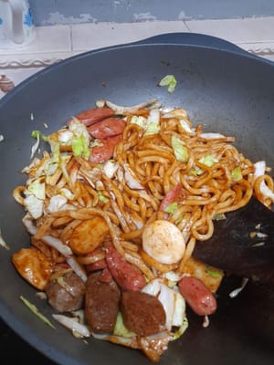 Aggiungere i noodles udon, la salsa di ostriche, la salsa di soia nera, il sale, il pepe e soffriggere fino a cottura ultimata.