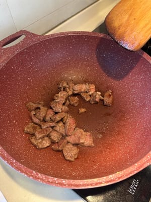 在加熱的平底鍋中倒入橄欖油，將切丁的牛扒煎至略呈褐色，然後盛出備用。