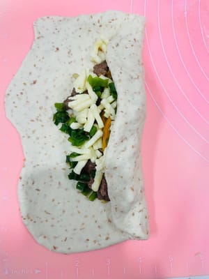 Sebarkan daging sapi giling yang sudah ditiriskan di atasnya, tambahkan keju mozzarella, lalu taburi dengan daun bawang cincang.