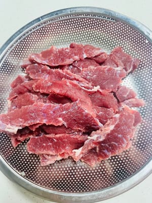 소고기를 씻어 물기를 빼고, 결 반대 방향으로 길게 채 썹니다. (튀기면 줄어들어 맛을 유지하기 쉽기 때문에 더 크게 썰어야 합니다.)
~~신선하고 부드러운 등심이나 안심을 고르기 어렵거나, 튀길 때 열이 너무 세게 가해지는 것이 걱정된다면, 고기를 재울 때 베이킹 소다 1g을 넣어보세요. 베이킹 소다는 약알칼리성으로 소고기의 섬유 구조를 파괴하여 물을 더 많이 흡수하게 하고 고기를 더 부드럽게 만들 수 있습니다.