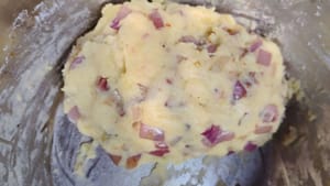 Versez le mélange cuit sur la purée de pommes de terre, ajoutez un peu de sel et mélangez bien en portant des gants.