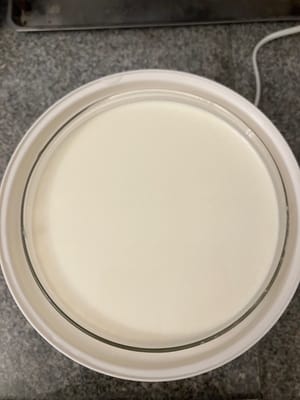 牛乳を入れたガラス容器をヨーグルトマシンに入れる