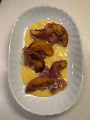 将煎好的桃子叠放在意大利熏火腿上，看起来更美观。