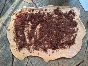 Luego esparce los rellenos de azúcar y canela uniformemente sobre la hoja.