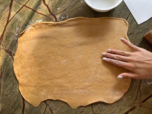 Prepara un poco de agua y humedece ligeramente la hoja con un poco de agua para que se adhiera mejor el relleno de azúcar y canela.
