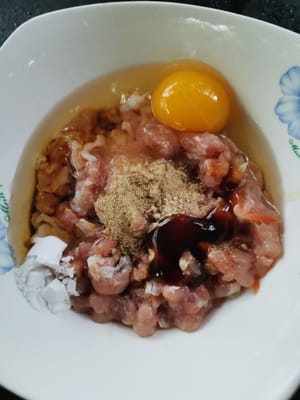 Das Hähnchen würzen (Salz, Pfefferpulver, Sojasauce, Zucker, Ingwer, Ei) und umrühren, bis alles gleichmäßig vermischt ist.